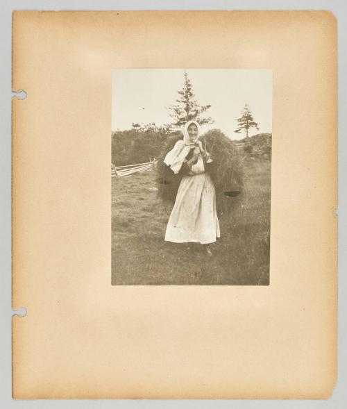 [A woman carries bushels of branches for firewood on her back]. Page 48 of Newfoundland from Collection of Canadian albums compiled by Edith S. Watson