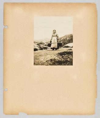 [A woman wears a hoop and pails with rocky hills behind her] Page 42 of Newfoundland from Collection of Canadian albums compiled by Edith S. Watson
