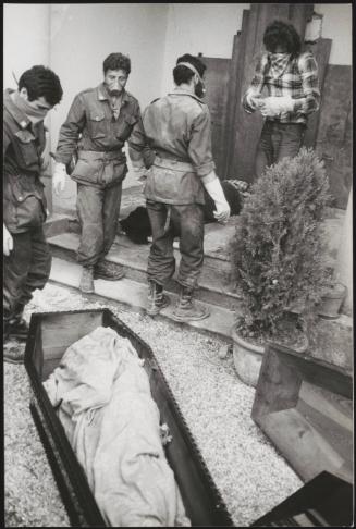 Soldiers and volunteers with covered faces work at preparing the victim's bodies for burial at the Osoppo cemetery after the 1976 Friuli earthquake