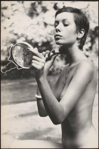 The actress Sonia Ciuffi sits topless and brushes her hair in a mirror