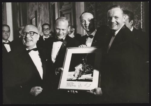 The astronauts from Apollo 11, Neil Armstrong, Michael Collins and Buzz Aldrin being presented with a framed photo of their landing on the moon 