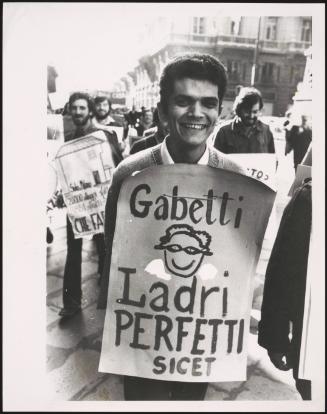 A young man from the housing union of Italy smiles and shows off his protest placard denouncing the real estate company 'Gabetti'