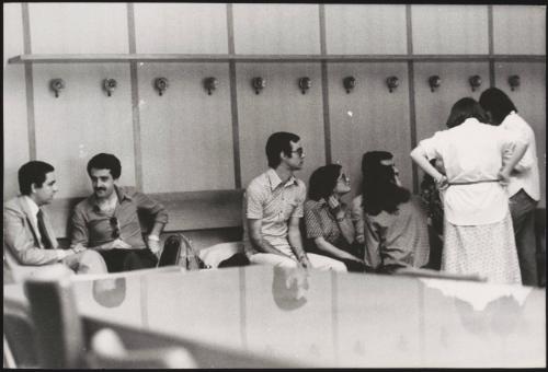 A group of students sitting along a bench in a university building