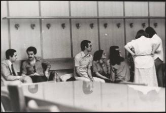A group of students sitting along a bench in a university building
