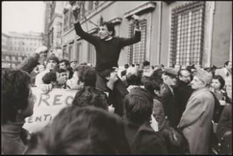 A man sits on another man's shoulders at a protest 