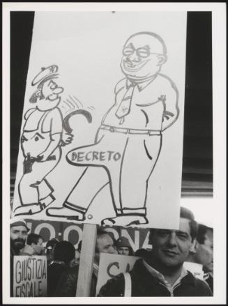 A hand drawn protest placard of a satirical illustration of Bettino Craxi also containing the word 'Decreto', meaning 'decree'