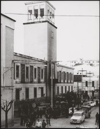 People gathered around on the pavement outside a state building