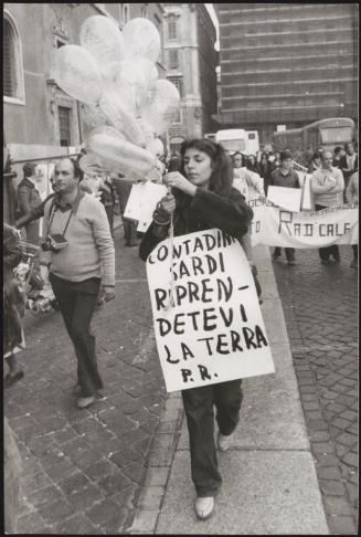 A woman carrying balloons and a poster calling for Sardinians' rights to their land, against military bases being set up there