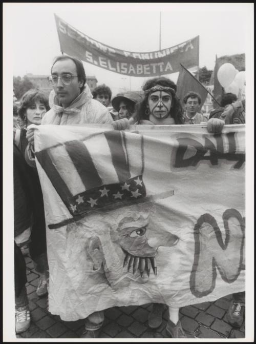 A man and woman marching with a hand painted banner at an anti-American protest 