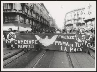 Milan 1982. A crowd of protesters march behind a large banner from the Florence quarter of the P.C.I, down a street at a communist  peace march 
