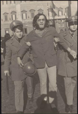 A protester is escorted away from a monarchist demonstration