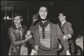 A protester is escorted away from a monarchist demonstration