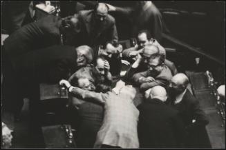 A group of politicians huddle together during a sesion in Parliament 