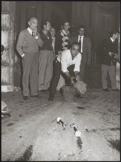 A man throws sand from a bucket on to the street