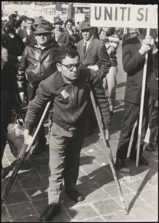 A man with crutches joins in a protest march for the disabled