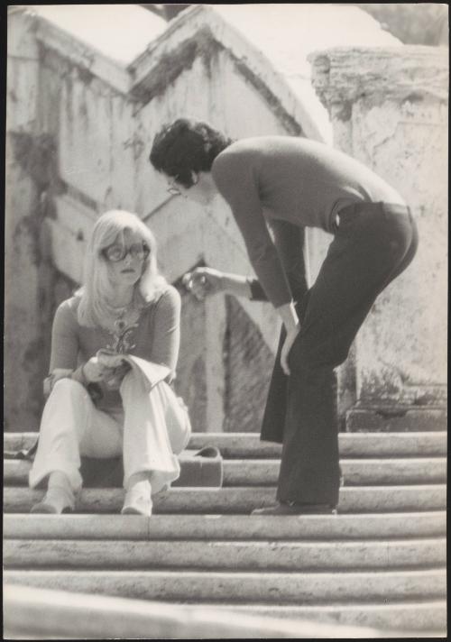 An Italian 'Pappagalli' man approaches a femlae tourist on the steps of Trinità dei Monti, Rome