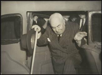 Former Prime Minister of Italy, Francesco Saverio Nitti, exiting a car holding a walking stick and hat