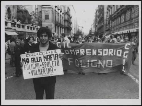 At a trade union protest, a man holds up a 'No to the Mafia' placard