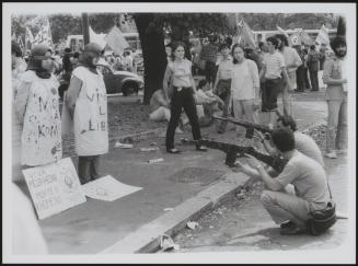 Two men aim their wooden rifles at two blindfolded women in a protest against Iranian leader Khomeini 