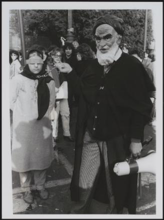 A masked charicature of Iranian leader Khomeini in a satirical re-enacment of the leader imprisoning and executing members of the opposition 