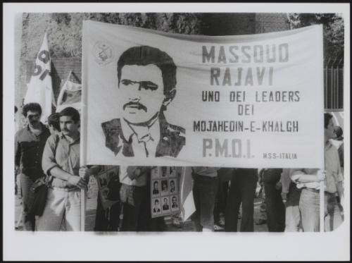 Young men holding a banner to the People's Mojahedin of Iran (or the Mojahedin-e-Khalq (MEK), also PMOI or MKO), founded in 1965 by a group of left-leaning Muslim Iranian university students