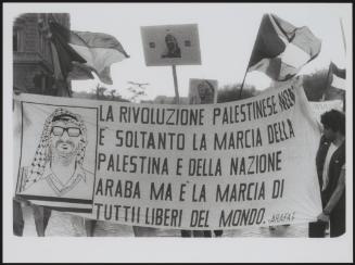 People hold a banner with a drawing of Yasser Arafat, that reads 'The Palestinian revolution is not only the march of Palestine and the Arab but of all those who are free around the world'