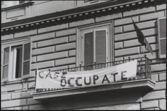 Squatters in an empty house make it clear they have the rights to live there - hanging a banner from the balcony which reads 'Squats', or 'this house is occupied'