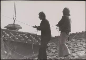 Two men on a city roof raise protest banners