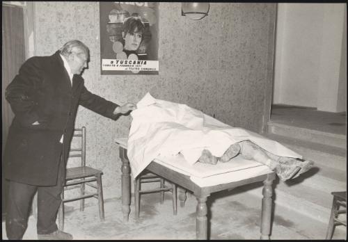 A man looks at a victim laid under a sheet in the aftermath of an earthquake, 1971