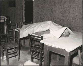 A man looks at a victim laid under a sheet in the aftermath of an earthquake, 1976