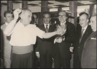 Giulio Andreotti and other politicians watch as a man pours sherry