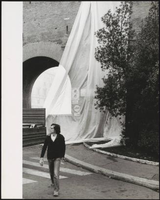 The erection of The Wall – Wrapped Roman Wall, Via Veneto and Villa Borghese, Rome, Italy, 1973-74. By artists Christo and Jeanne-Claude. The artist Christo walks by. 