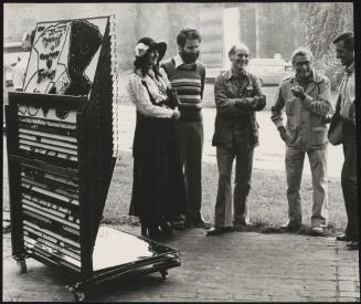 Four men and a woman standing near a stack of artist prints and sharing a joke; CORNEILLE, "PINOCCHIO"