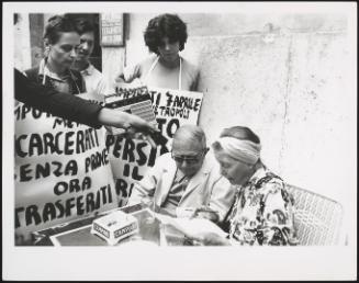 Demonstrators ask a couple at a table to sign a petition