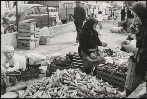 Women selling piles of peppers and other vegetables at a street market