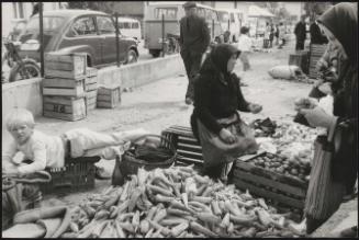 Women selling piles of peppers and other vegetables at a street market