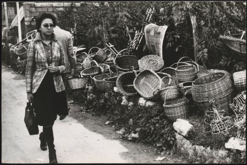 A womanwalks by wicker baskets for sale, lining the road on market day
