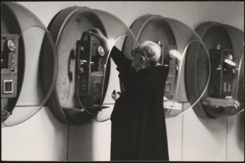 A priest feeds coins into a pay box telephone at an airport