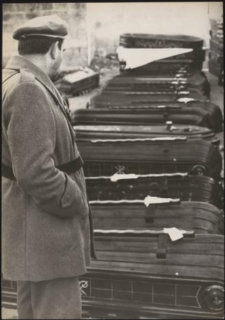A solider looks at a long line of new coffins on the ground ready for the victims of the Belice earthquake in Sicily 1968