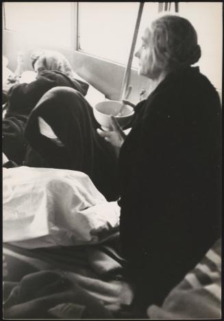 A woman eats a bowl of soup in temporary shelter in the aftermath of the Belice earthquake, Sicily 1968