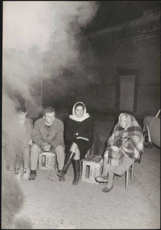 Four refugees, displaced from their homes after the Belice earthquakes, sit by a fire at night 