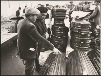 Men gather round new coffins laid side by side and stacked on the ground in preparation for the victims of the Belice earthquake in Sicily 1968