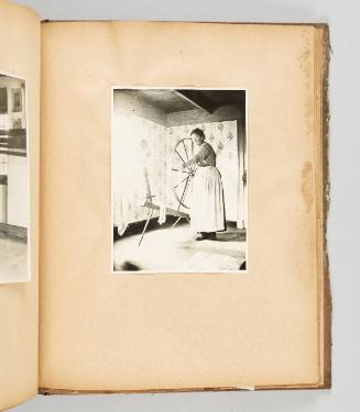 [A woman works on a very large spinning wheel in a sun-drenched room] [Page 54 of Quebec I; from collection of Canadian albums compiled by Edith S. Watson, 1890s-1930s.]