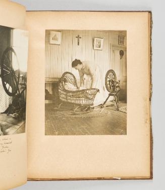 [Woman tends to her baby in a wicker cradle, with her spinning wheel nearby] [Page 42 of Quebec I; from collection of Canadian albums compiled by Edith S. Watson, 1890s-1930s.]