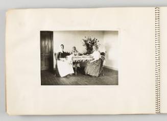 [Three women sitting at dining table with large bouquet of flowers, page 38 of The Doukhobors I album]