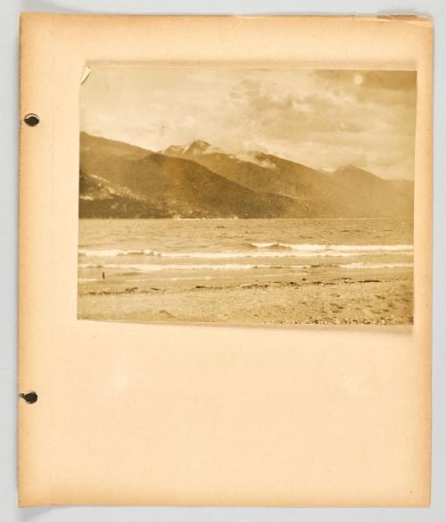 [Waves along the shore with mountains and clouds in background]