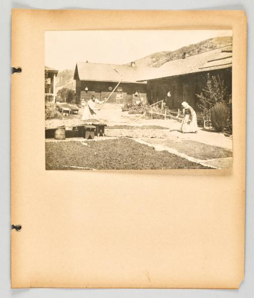 [Two women working with tools in a courtyard, in a Doukhobor community.] [Page 57 of The Doukhobors II album]