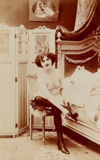 [Woman seated on chair bed, wearing black stockings]