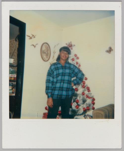 Getting Ready For School, 12-13-85 [Girl in blue plaid shirt posing in front of christmas tree]