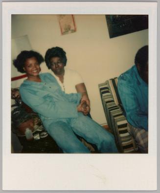 [Woman sitting on man's lap holding hands and smiling]
